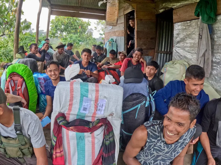 Expedition team of collaborators, local community members, and students resting with packed gear at a field hut