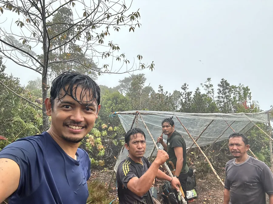 Heru with the field team building a camp shelter in the mist