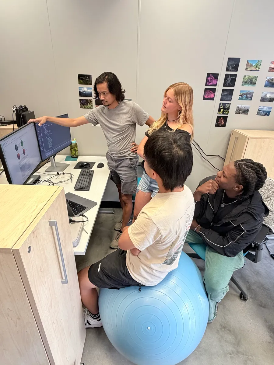 Heru walking students through code and results on a monitor